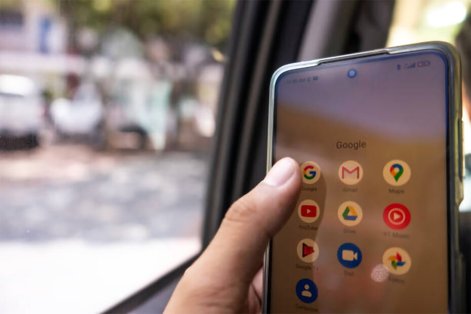 um homem dentro de um carro com um celular na mão abrindo o app do Google